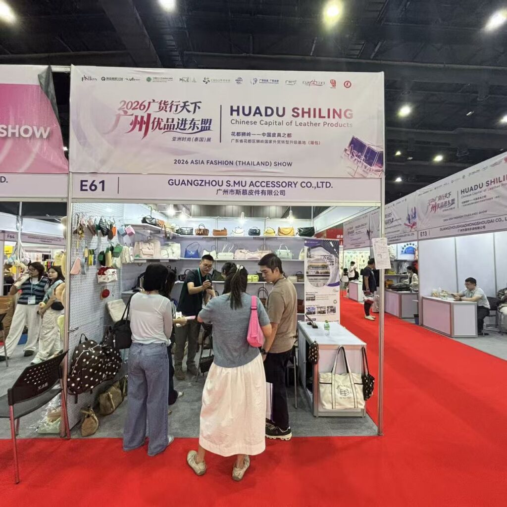 International buyers reviewing custom handbag samples with S.MU ACCESSORY at Booth E61 in Bangkok.